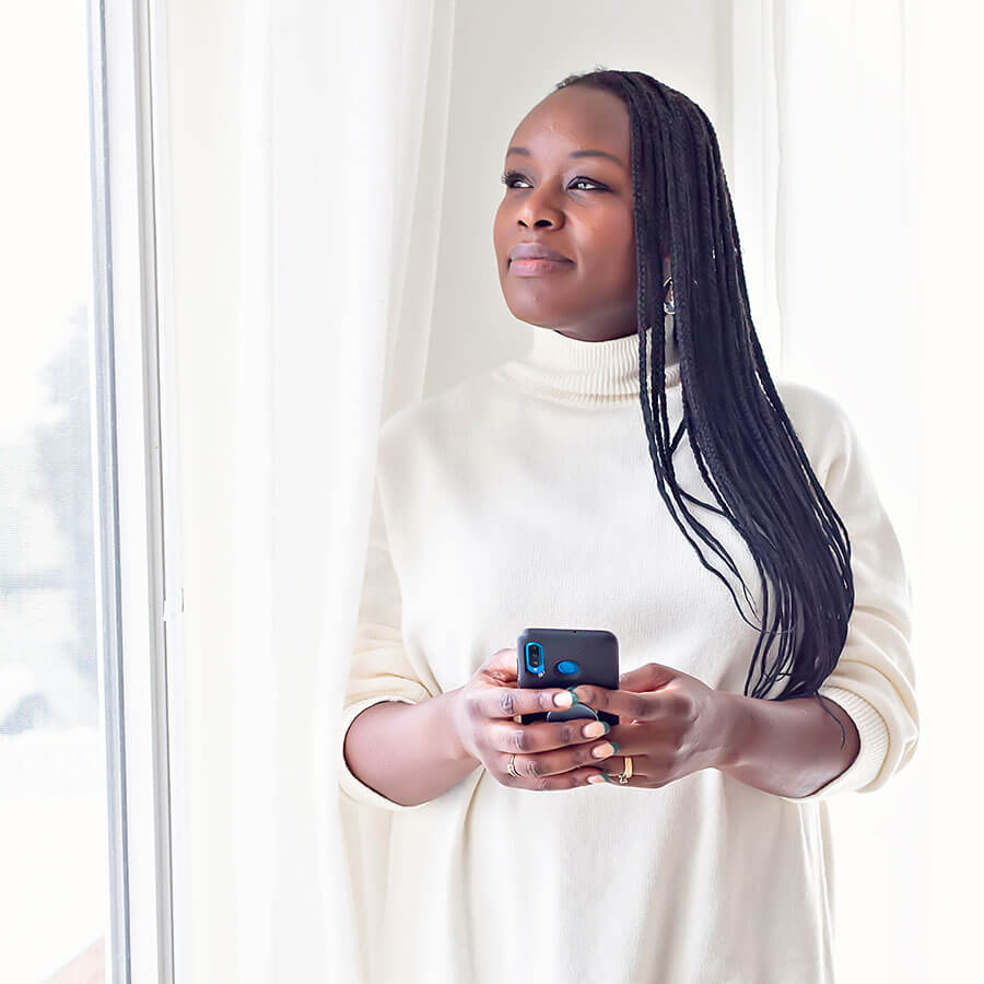 woman looking out window musingly holding phone